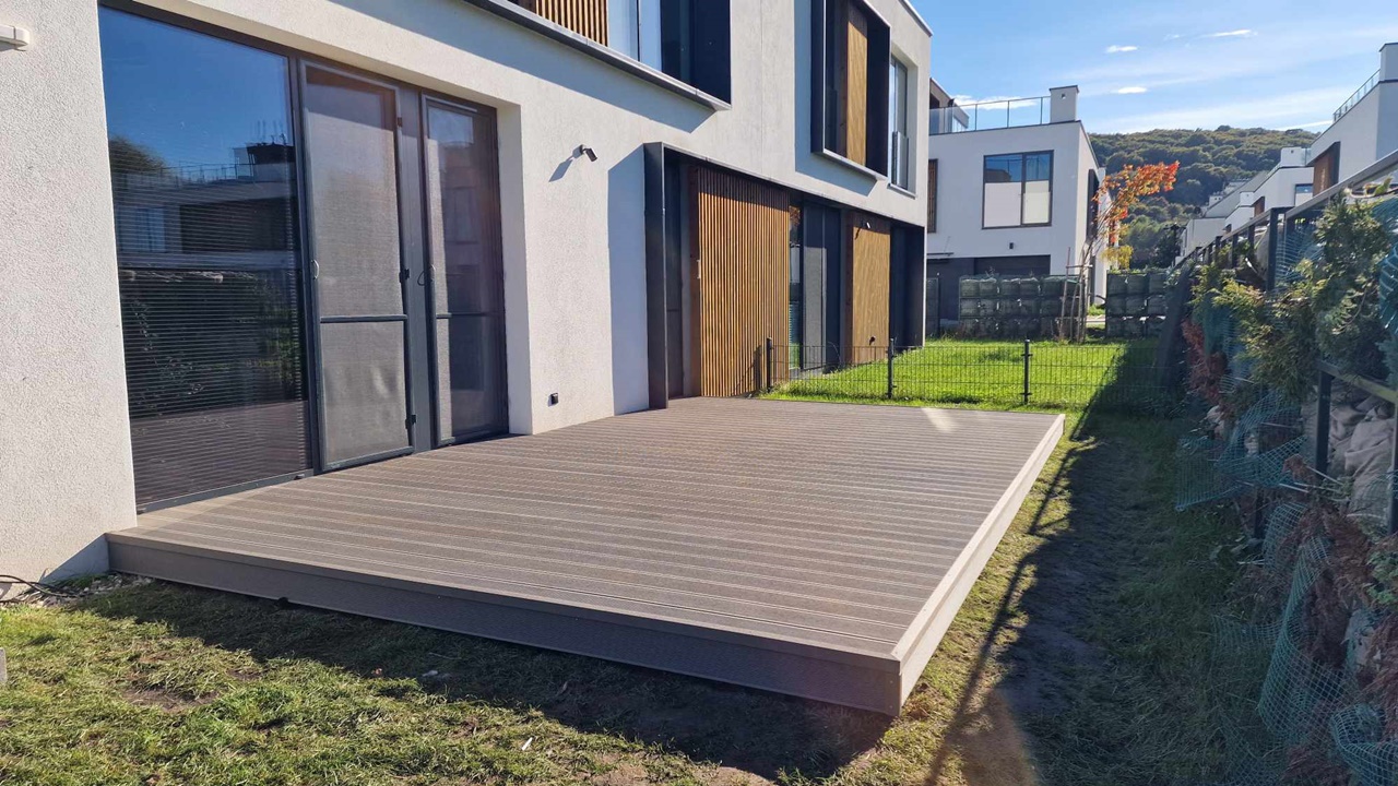 A light brown composite decking board terrace installed beside a modern house.