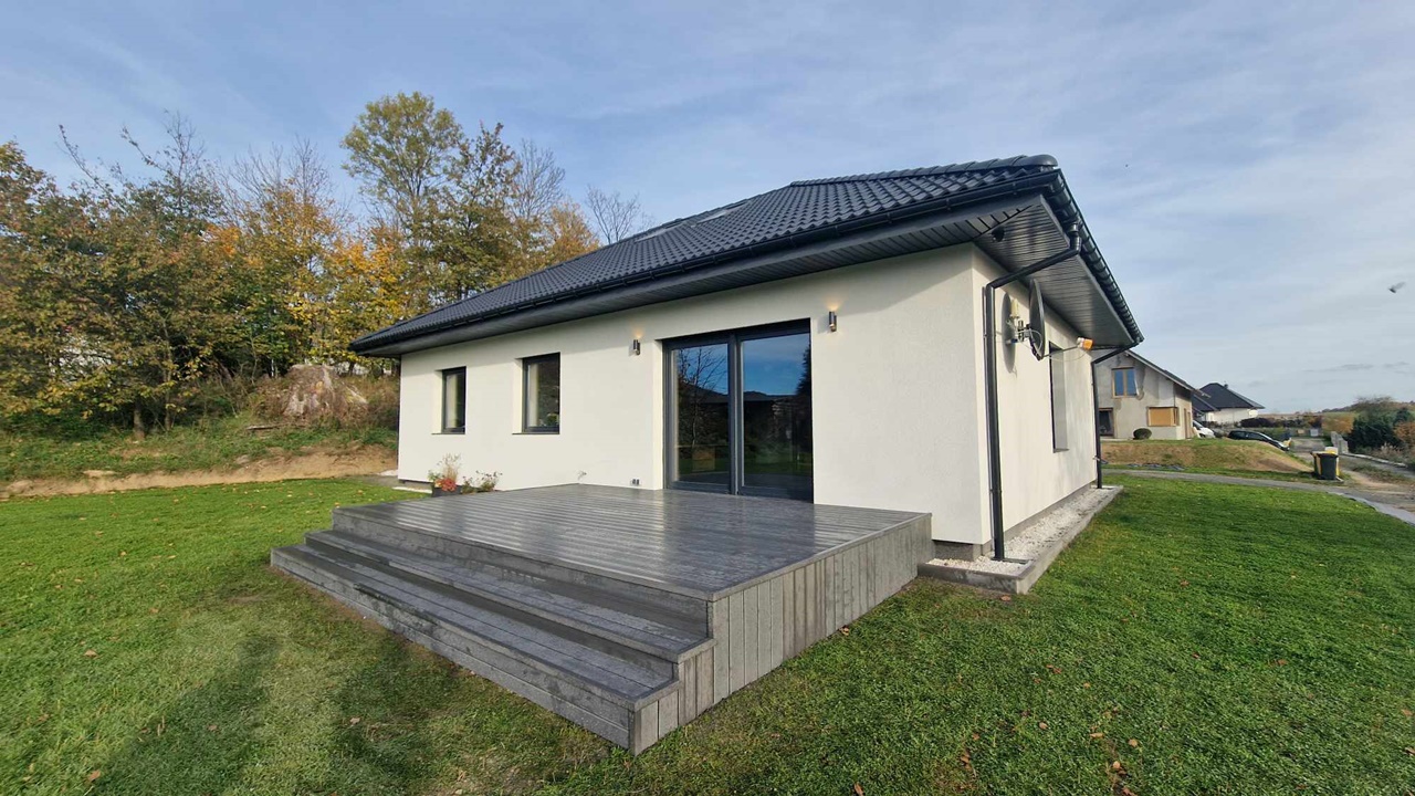 A terrace made from light grey Select composite decking boards, with steps beside a white detached house.