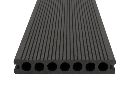 Cross-section of a dark composite decking board with round chambers and a grooved surface.