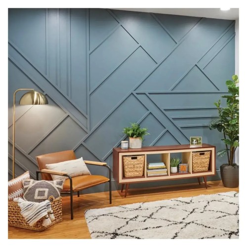 A blue wall with a geometric pattern of DIY decorative strips in a living room with a leather armchair.