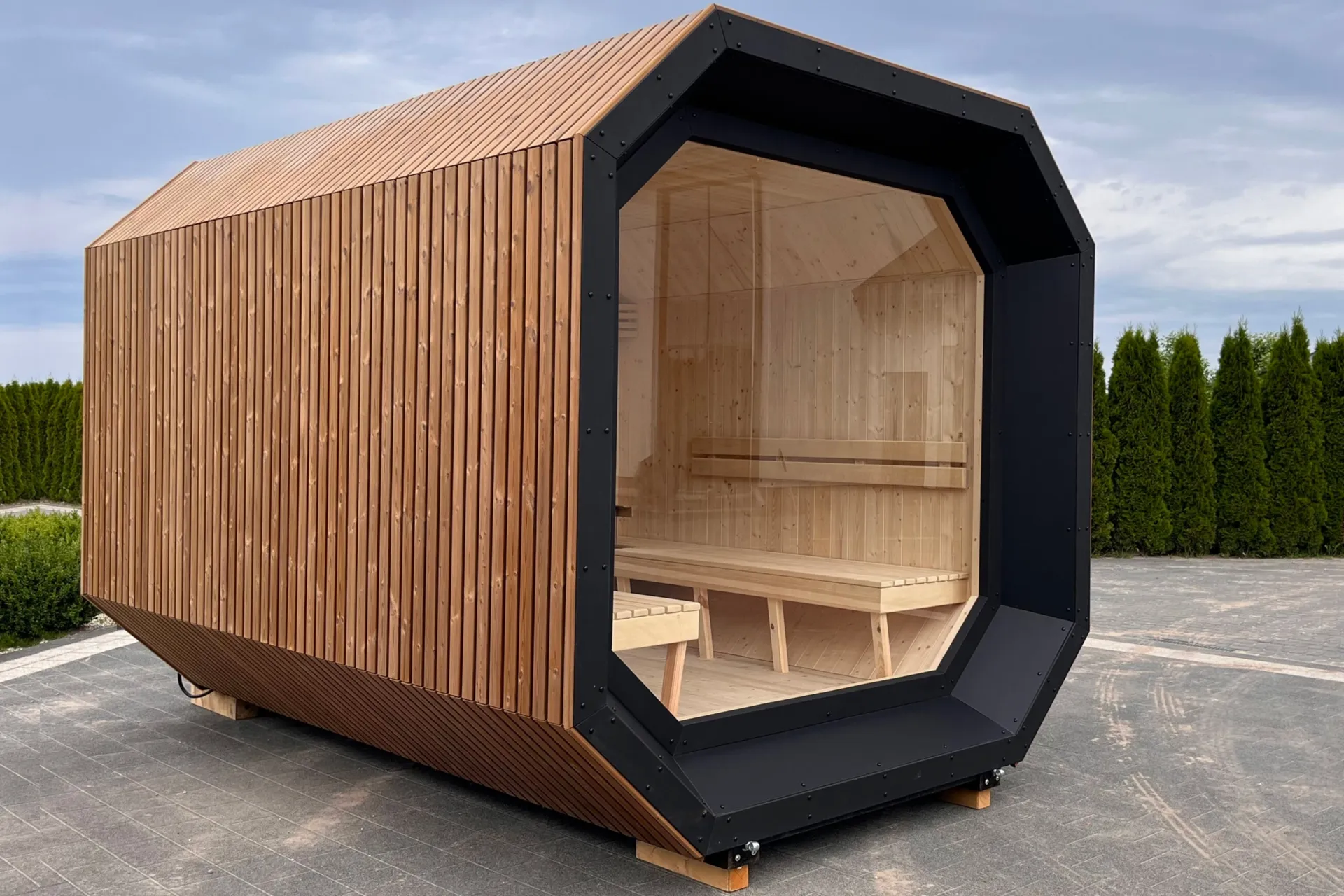 A modern Scandi garden sauna with a wooden slat façade and glazing revealing wooden benches.